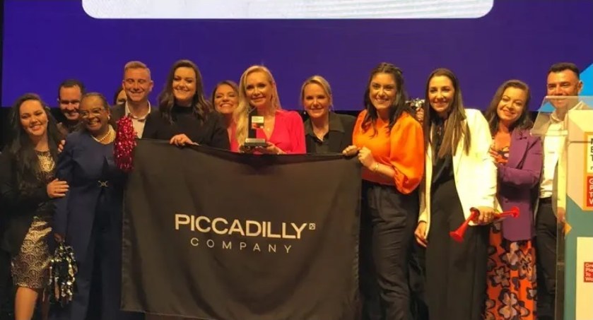 Tým Piccadilly na pódiu s firemní vlajkou při předávání ocenění